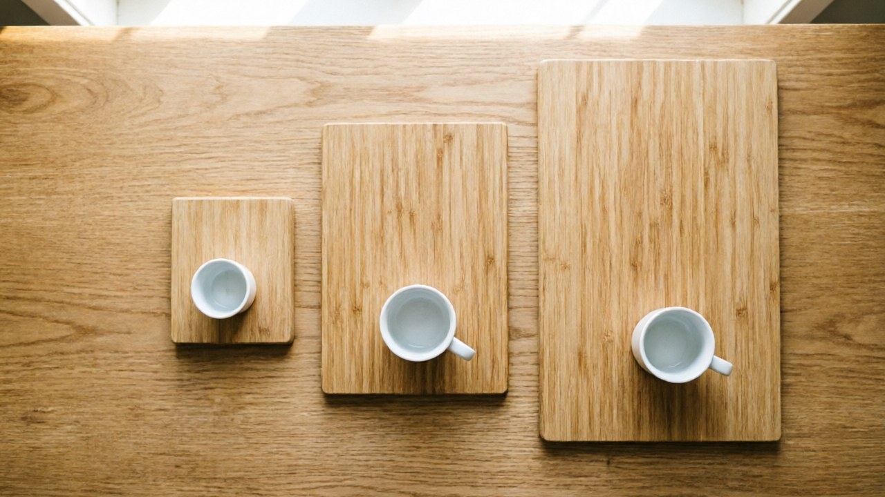 Three tea trays of different sizes lined up with a gaiwan and cups for scale