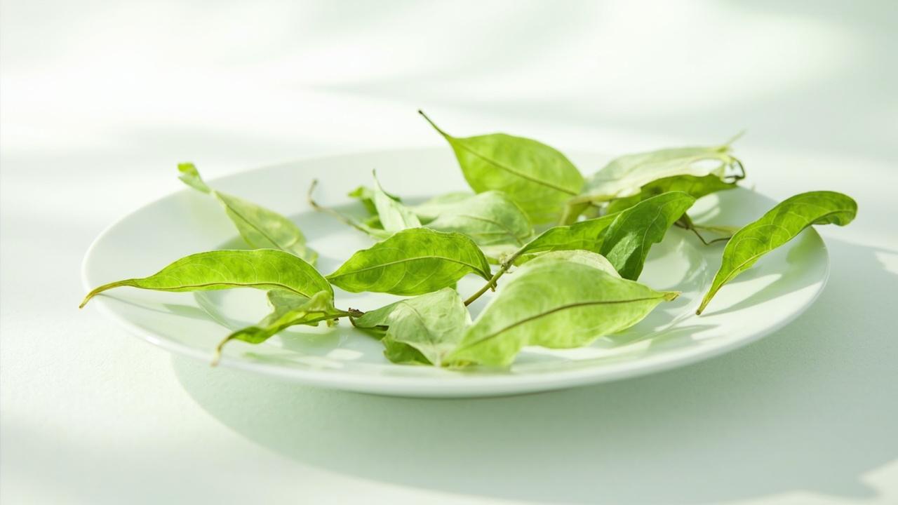 Flat jade-green Longjing tea leaves on a white surface.